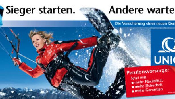 Eine Frau snowkited mit einem Snowboard vor einer Bergkulisse.