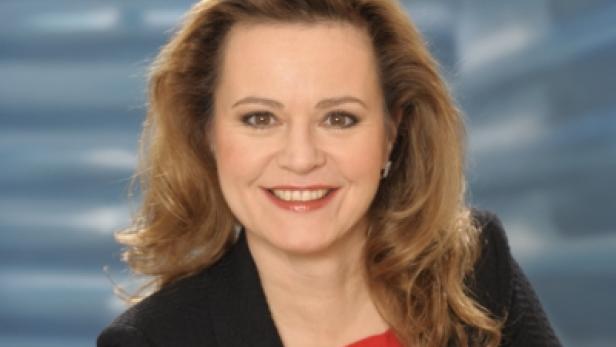 Porträt einer lächelnden Frau mit blonden, gewellten Haaren.