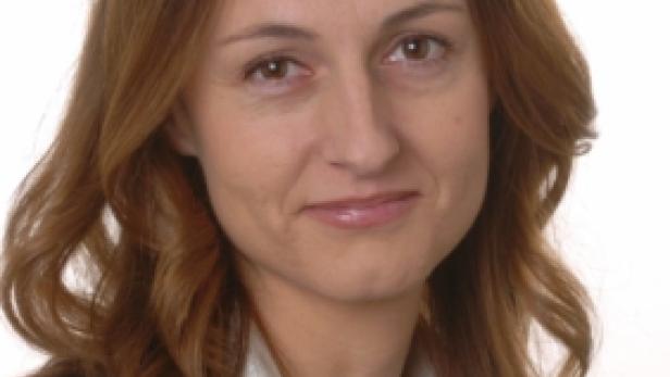 Porträt einer Frau mit braunen Haaren und einem schwarzen Blazer.