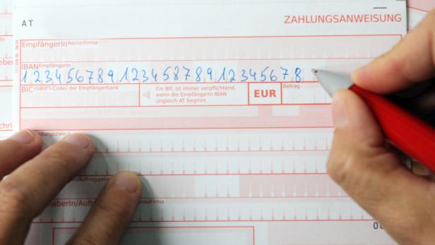 … Eine Person füllt eine Zahlungsanweisung mit einem roten Stift aus.