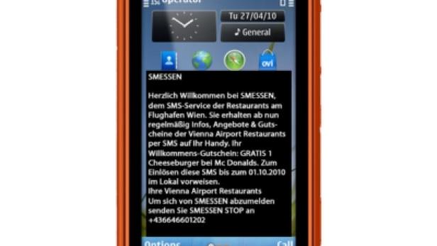 Ein orangefarbenes Nokia-Handy zeigt eine SMS-Nachricht von „SMESSEN“ mit einem Gutschein für einen Cheeseburger bei McDonald's.