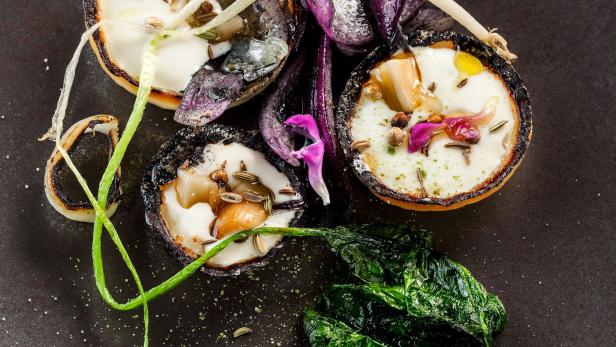 Drei gefüllte Zwiebelhälften mit Gemüse und Gewürzen auf einem Teller.