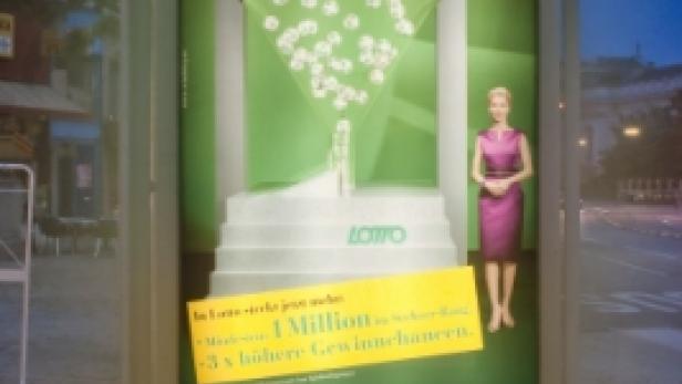 Eine Bushaltestelle zeigt eine Lotto-Werbung mit einer Frau und fallenden Lottokugeln.