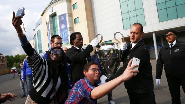 Fans machen Selfies mit der UEFA Champions League Trophäe vor dem Chelsea Football Club.