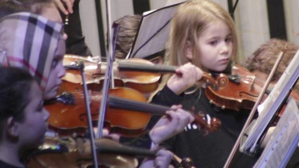 Eine Gruppe junger Menschen spielt Geige in einem Orchester.