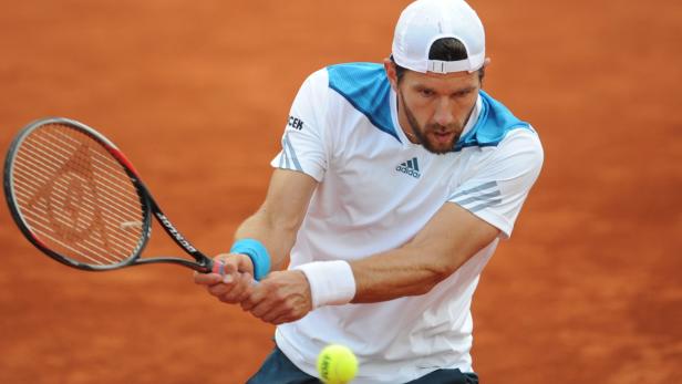 Ein Tennisspieler schlägt einen gelben Tennisball mit einem Schläger.