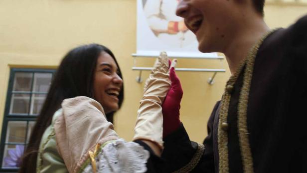 Zwei lachende Personen in historischen Kostümen halten Hände.