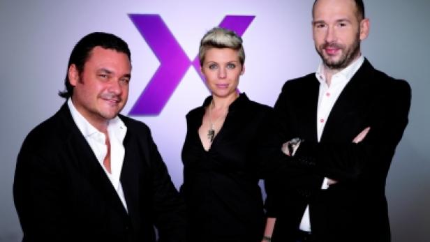 Drei Personen posieren vor einem lila X-Logo.