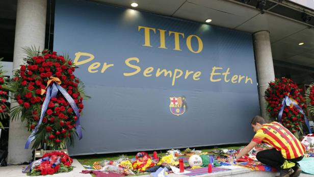 Ein Mann legt Blumen und Geschenke vor einem Banner für Tito Vilanova nieder.