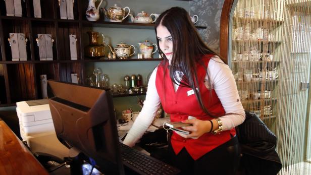 Eine Hotelangestellte arbeitet am Computer hinter dem Empfangstresen.