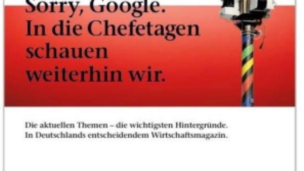 Eine Kamera auf einem farbig gestreiften Stativ vor dem Hintergrund einer Werbeanzeige.