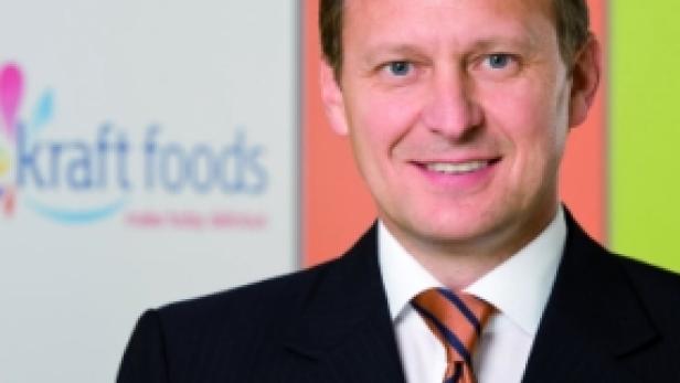 Ein Mann im Anzug steht vor einem farbenfrohen Hintergrund mit dem Kraft Foods Logo.
