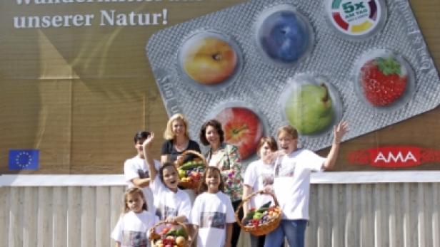 Kinder und Erwachsene präsentieren Obstkörbe vor einem Banner mit der Aufschrift „Wundermittel aus unserer Natur!“.