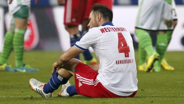 Ein Fußballspieler von Hamburger SV sitzt enttäuscht auf dem Rasen.