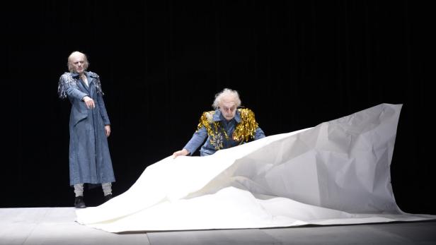 Zwei Schauspieler in Kostümen auf einer Bühne mit einem großen weißen Tuch.