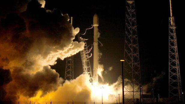 Eine Rakete startet bei Nacht mit einer großen Rauchwolke.