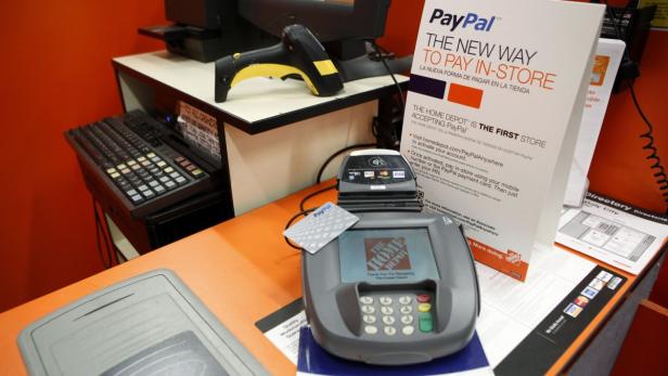 Ein Home Depot-Kassensystem mit einem PayPal-Kartenlesegerät und Hinweisschildern.
