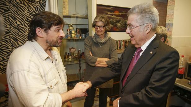 Ein Mann im Anzug schüttelt einem anderen Mann die Hand, während eine Frau zusieht.