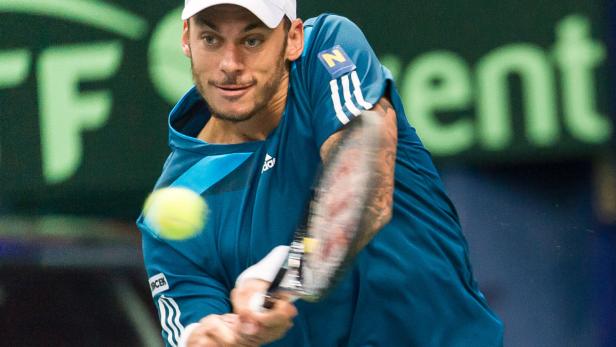Ein Tennisspieler schlägt einen gelben Tennisball.