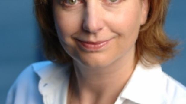 Eine Frau mit braunen Haaren und weißem Hemd lächelt in die Kamera.