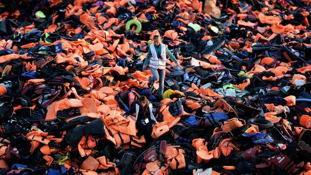 Eines der Fotos des Jahres: Freiwillige gehen auf Lesbos über Schwimmwesten