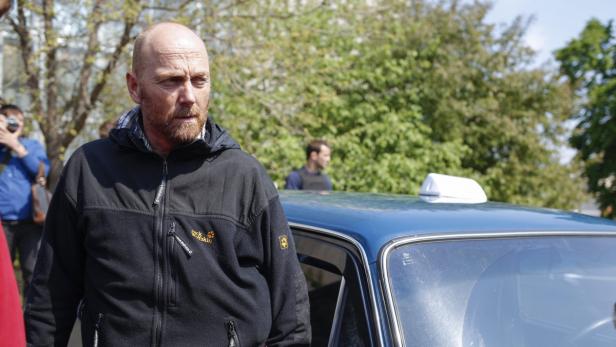 Ein Mann steht neben einem blauen Taxi.