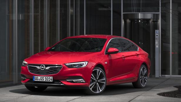Ein roter Opel Insignia vor einem modernen Gebäude mit Glasfassade.