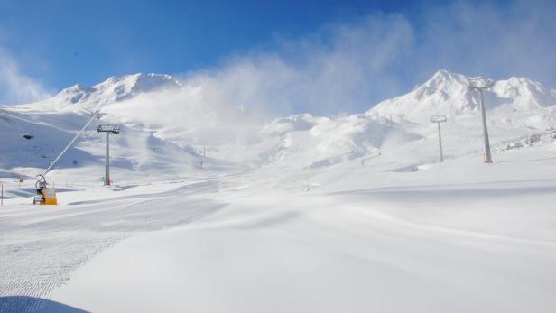 Eine verschneite Skipiste mit Skiliften vor einer Bergkulisse.