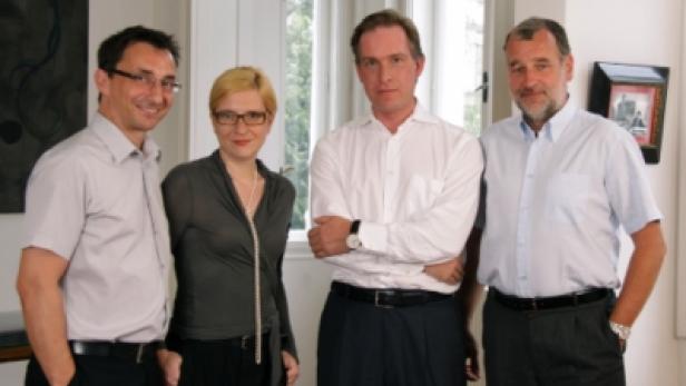 Eine Gruppe von vier Personen posiert für ein Foto in einem hellen Raum.