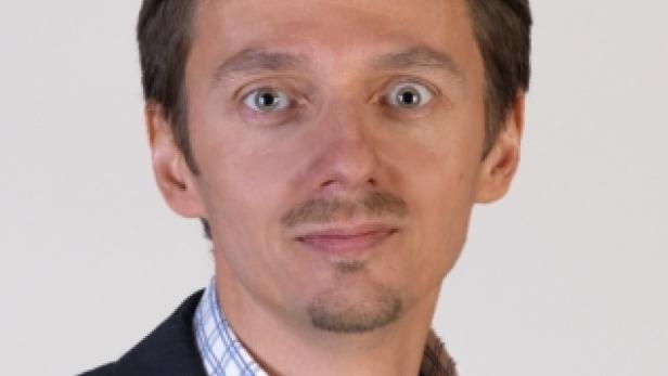 Porträt eines Mannes mit blau kariertem Hemd und dunklem Sakko.