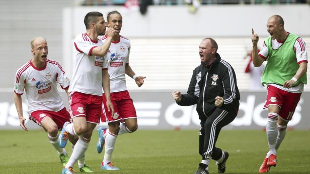 Fußballspieler und ein Trainer von RB Leipzig jubeln auf dem Spielfeld.