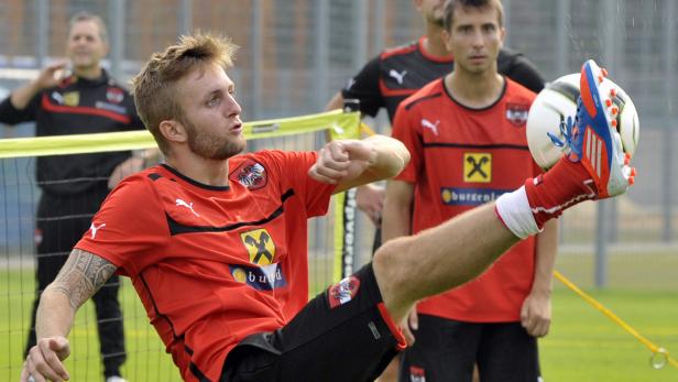 Ein Fußballspieler im rot-schwarzen Trikot der österreichischen Nationalmannschaft jongliert mit dem Ball.