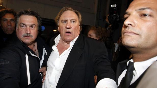 Gérard Depardieu wird von zwei Männern flankiert.