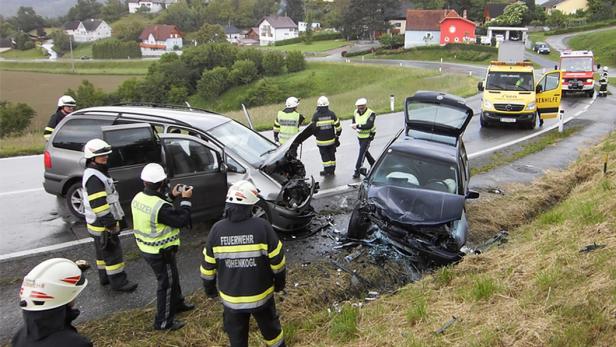 Nach einem Autounfall stehen Polizei und Feuerwehr an der Unfallstelle.