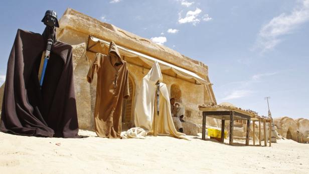 Dekorationen und Kostüme vor einem Gebäude in der Wüste, möglicherweise ein Star Wars Set.