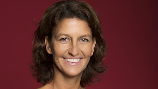 Eine lächelnde Frau mit braunen Haaren vor einem roten Hintergrund.