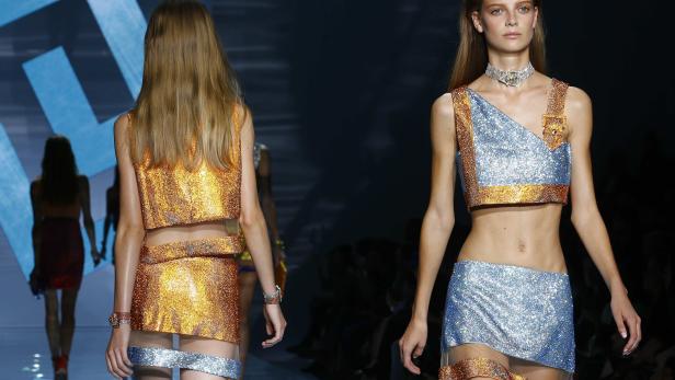 Models präsentieren glitzernde zweiteilige Outfits auf einem Laufsteg.