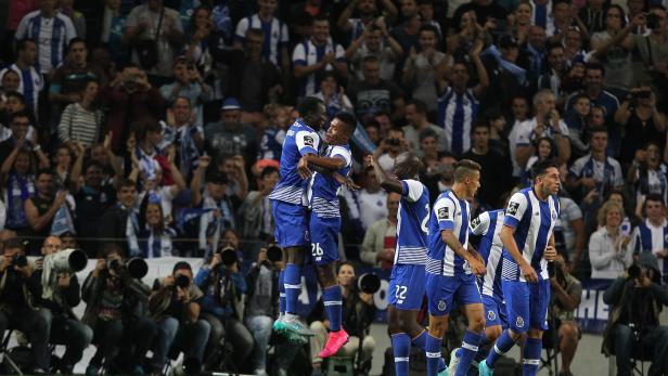 Zwei Fußballspieler in blau-weißen Trikots umarmen sich vor einer jubelnden Zuschauermenge.
