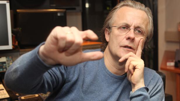 Ein Mann mit Brille gestikuliert mit den Fingern vor einem Mischpult.