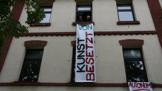 An der Fassade eines Hauses hängt ein Banner mit der Aufschrift „Kunst besetzt“.