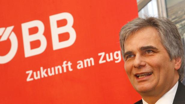 Ein Mann steht vor einem roten ÖBB-Logo mit dem Slogan „Zukunft am Zug“.