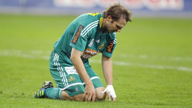Ein Fußballspieler kniet mit gesenktem Kopf auf dem Rasen.