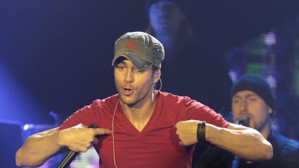 Enrique Iglesias tritt in einem roten T-Shirt und einer Kappe auf einer Bühne auf.