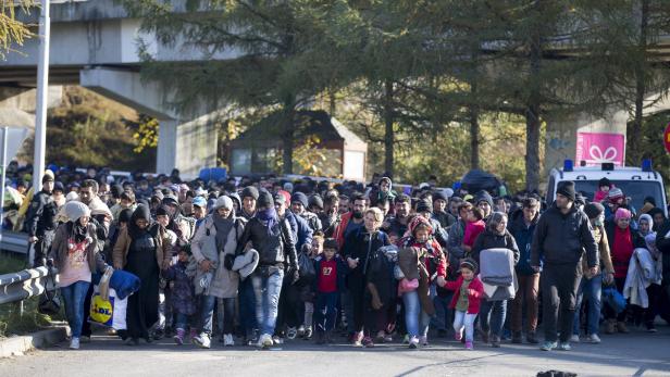 Eine große Gruppe von Flüchtlingen geht eine Straße entlang.