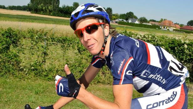 Ein Radfahrer mit Helm und Sonnenbrille gibt einen Daumen nach oben.