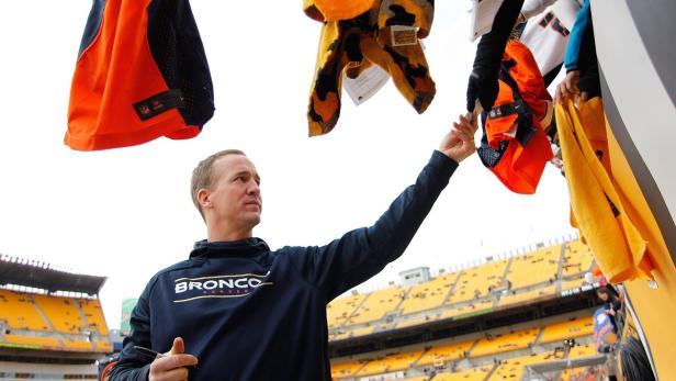Peyton Manning signiert Fanartikel vor einem Footballspiel.
