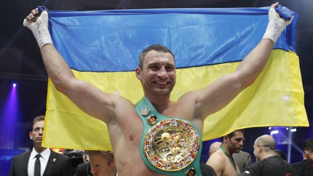 Vitali Klitschko feiert mit der ukrainischen Flagge und seinem Weltmeistertitel.