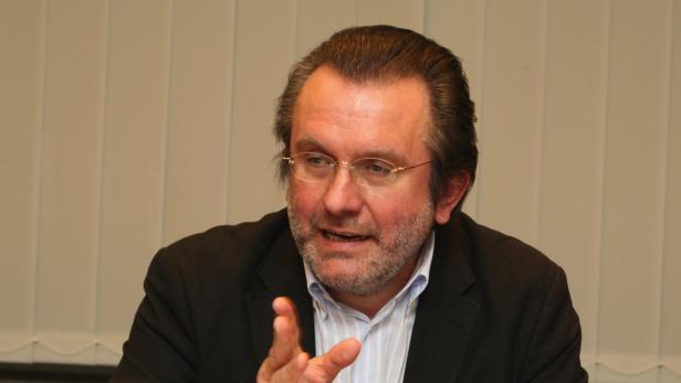 Ein Mann mit Brille und Bart gestikuliert während eines Gesprächs.