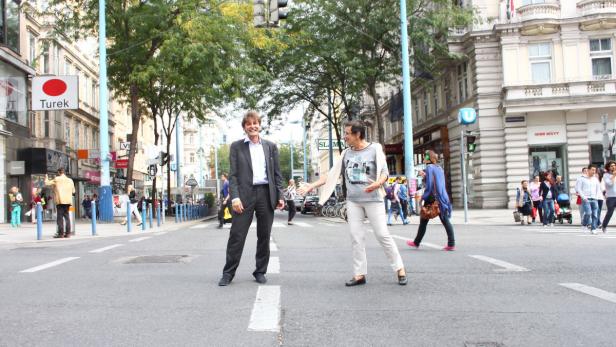 Ein Mann im Anzug und eine Frau stehen auf einer belebten Straße in Wien.