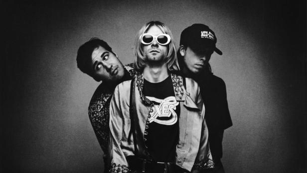 Schwarzweißaufnahme von Kurt Cobain mit zwei weiteren Personen.